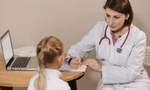 Lekarka pisze zwolnienie lekarskie do szkoły dla małej pacjentki.