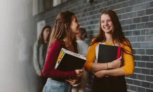 Dwie uczennice rozmawiają, trzymając książki. Czy to szkoła drugiego wyboru? Co to znaczy dla ich przyszłości?
