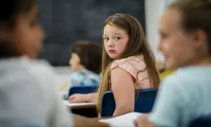 Smutna dziewczynka w szkole, która czuje się źle. Warto wiedzieć, gdzie zgłosić nękanie dziecka w szkole, by zapewnić mu bezpieczeństwo.