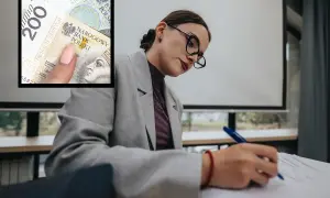 Kobieta w okularach pisze, a obok widać banknot 200 zł. Czy to symbol niskich zarobków w oświacie?