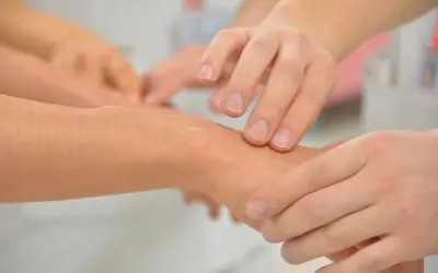 Terapia zajęciowa: dłonie terapeuty badają nadgarstek pacjenta. To pierwszy krok, by dowiedzieć się, jak zostać terapeutą zajęciowym.