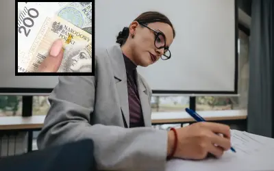 Kobieta w okularach pisze, a obok widać banknot 200 zł. Czy to symbol niskich zarobków w oświacie?