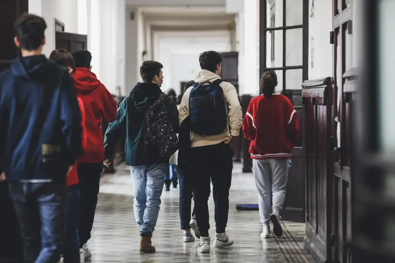 Uczniowie idą korytarzem. Może to być dzień rekrutacji uzupełniającej do szkół średnich, gdzie młodzi ludzie szukają swojej drogi.