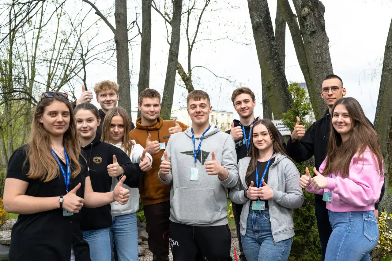 Grupa młodych ludzi z uśmiechem i kciukami w górze. Czy to szkoła zaoczna co to? Tak, to oni, przyszli studenci, którzy wybrali elastyczną ścieżkę nauki.