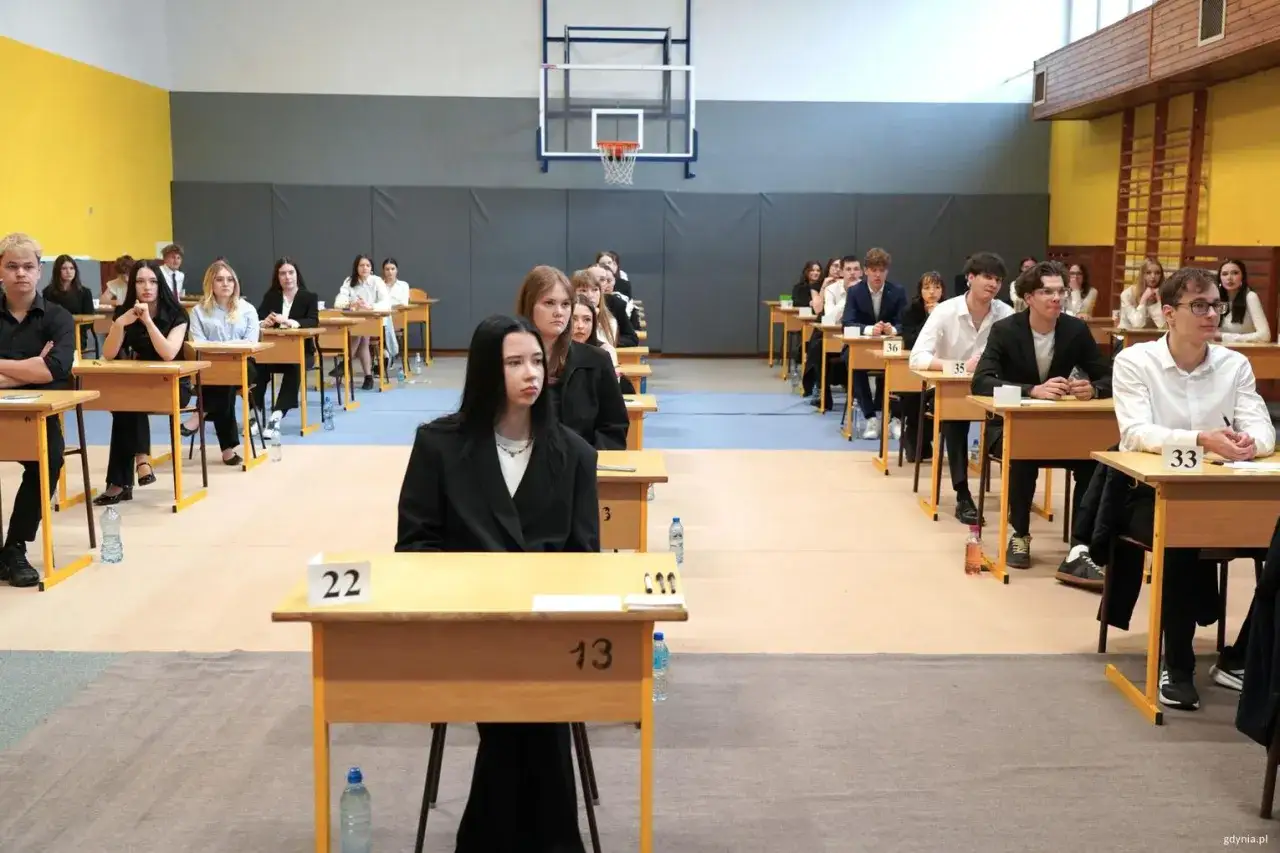 Uczniowie siedzą w ławkach podczas egzaminu. To ważny moment, by zdać maturę z matematyki.
